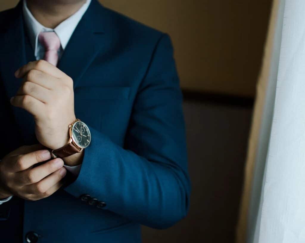 punctual man wearing a watch adjusting his suit