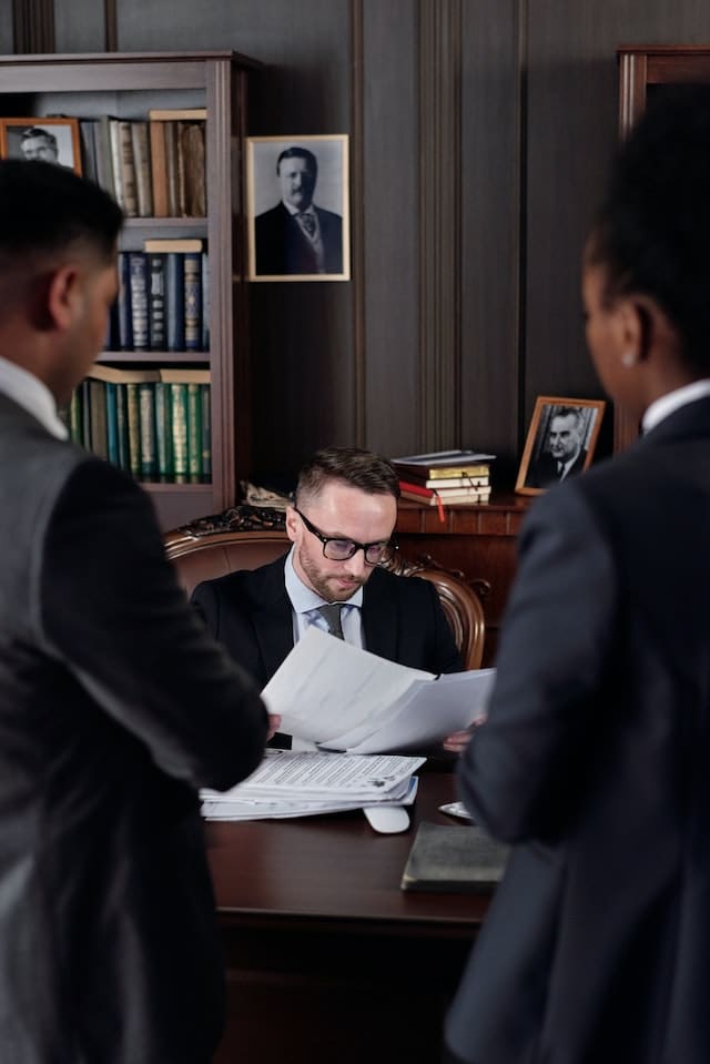 People gathered holding papers and filling out legal forms to file a case in Small Claims Court, with a gavel and law books in the background